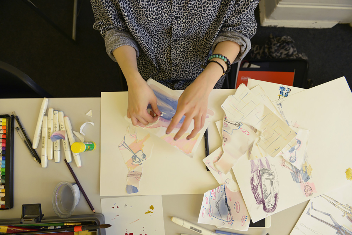 Hand holding pencil working on colourful sketches