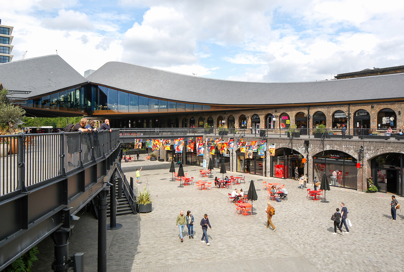 Zoomed out shot of Coal Drops Yard, with the multicoloured raised flags visible in the distance