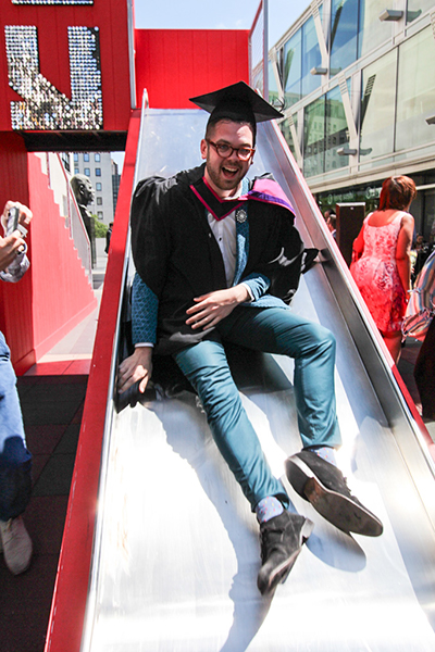 Liam Moore celebrates receiving his BA in Graphic Design Communication on one of the Southbank's slides.