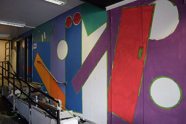 One section of the right hand side of the wall. The basic block colours of blue and purple are complete with orange and red rectangles cutting into the main blocks. White circles and a large white rectangle still awaits painting