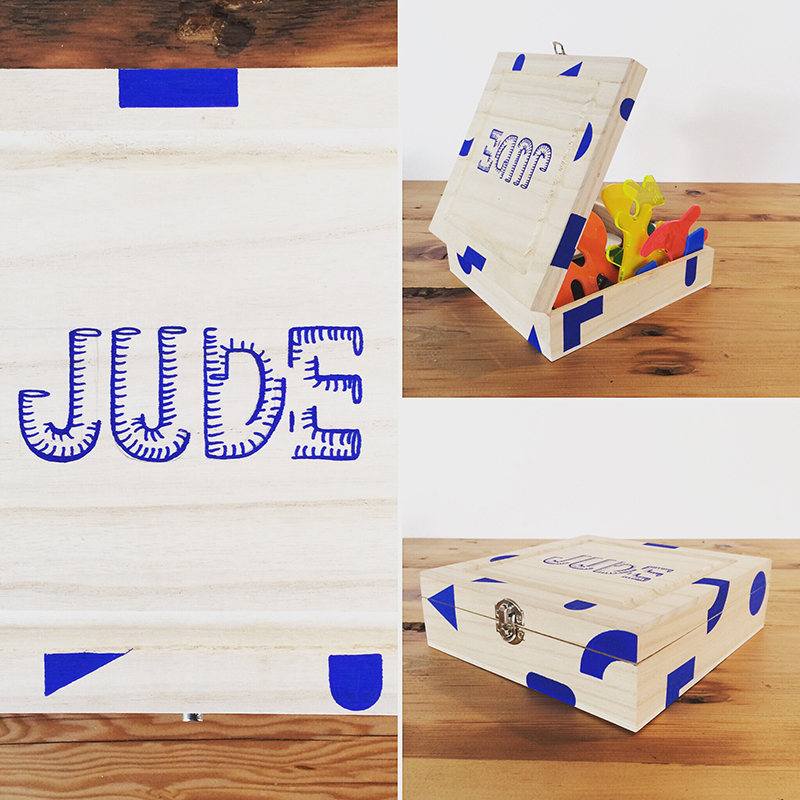 Eve Laguë, a playful object she has made. Simplistic, allowing those who interact with them to explore playful avenues upon interaction. This wooden box is simply but beautifully decorated with the name Jude and some geometric designs. In this image the box is being used to store small toy items.