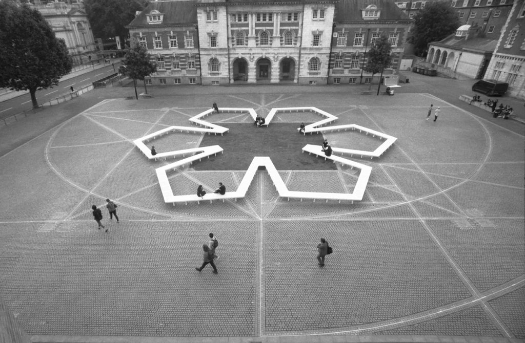 Aerial view of Pentagon Petal by artist Fran Cottell and architect Marianne Mueller, an art installation at Chelsea College of Arts, UAL which is open to the public until 30 July 2016. This project on the on the Rootstein Hopkins Parade Ground re-enacts a scaled version of Millbank Prison's plan, editing and reinterpreting it into a more socially active figure: a 120m long flower shaped bench.