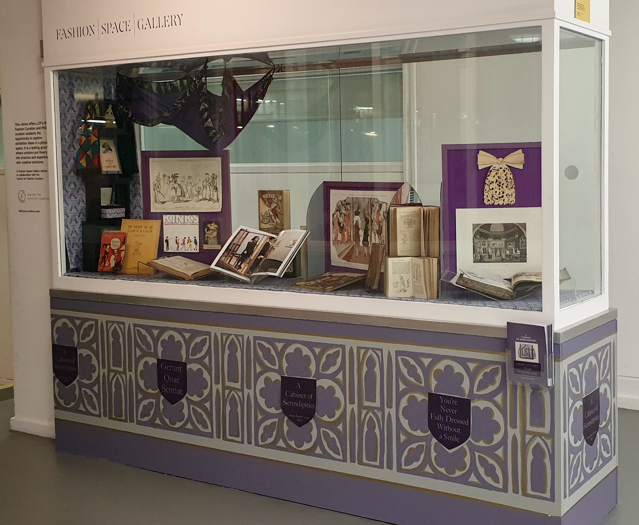 Glass cabinet labelled Fashion Space Gallery with small exhibition artefacts