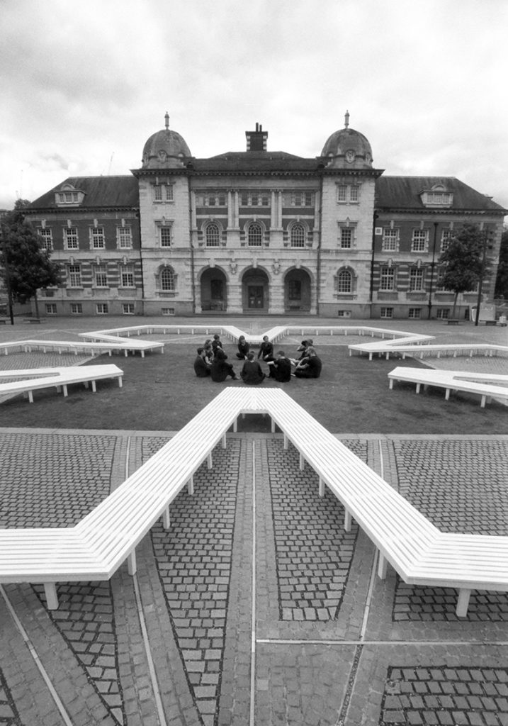 View of Pentagon Petal by artist Fran Cottell and architect Marianne Mueller, an art installation at Chelsea College of Arts, UAL which is open to the public until 30 July 2016. This project on the on the Rootstein Hopkins Parade Ground re-enacts a scaled version of Millbank Prison's plan, editing and reinterpreting it into a more socially active figure: a 120m long flower shaped bench.