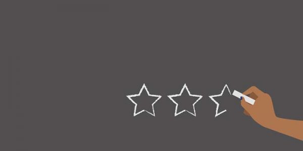 image of grey space with 3 chalked stars in bottom right; hand holding chalk completing third star.