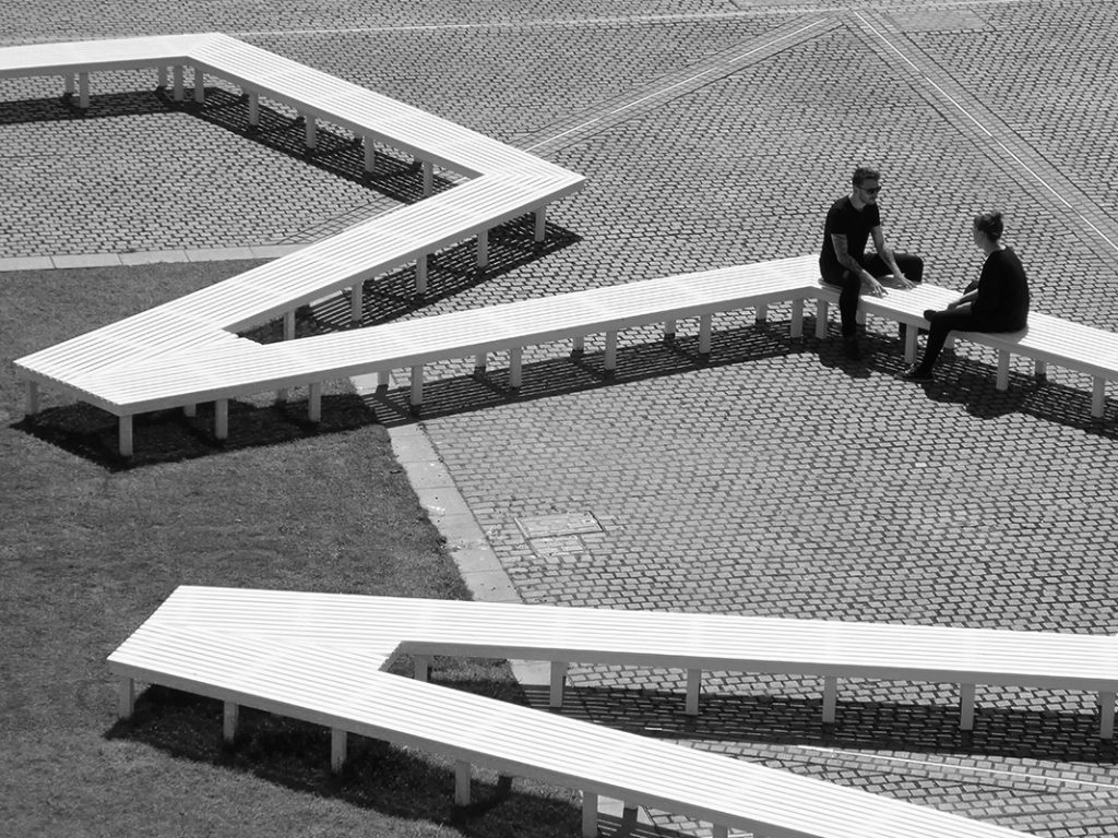 View of Pentagon Petal by artist Fran Cottell and architect Marianne Mueller, an art installation at Chelsea College of Arts, UAL which is open to the public until 30 July 2016. This project on the on the Rootstein Hopkins Parade Ground re-enacts a scaled version of Millbank Prison's plan, editing and reinterpreting it into a more socially active figure: a 120m long flower shaped bench.