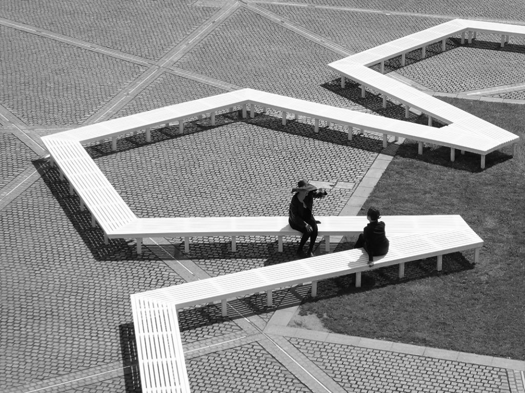 View of Pentagon Petal by artist Fran Cottell and architect Marianne Mueller, an art installation at Chelsea College of Arts, UAL which is open to the public until 30 July 2016. This project on the on the Rootstein Hopkins Parade Ground re-enacts a scaled version of Millbank Prison's plan, editing and reinterpreting it into a more socially active figure: a 120m long flower shaped bench.