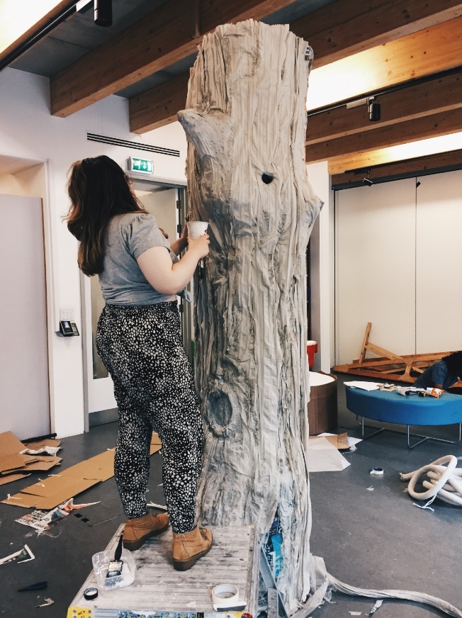 Student working on a large tree prop for the set