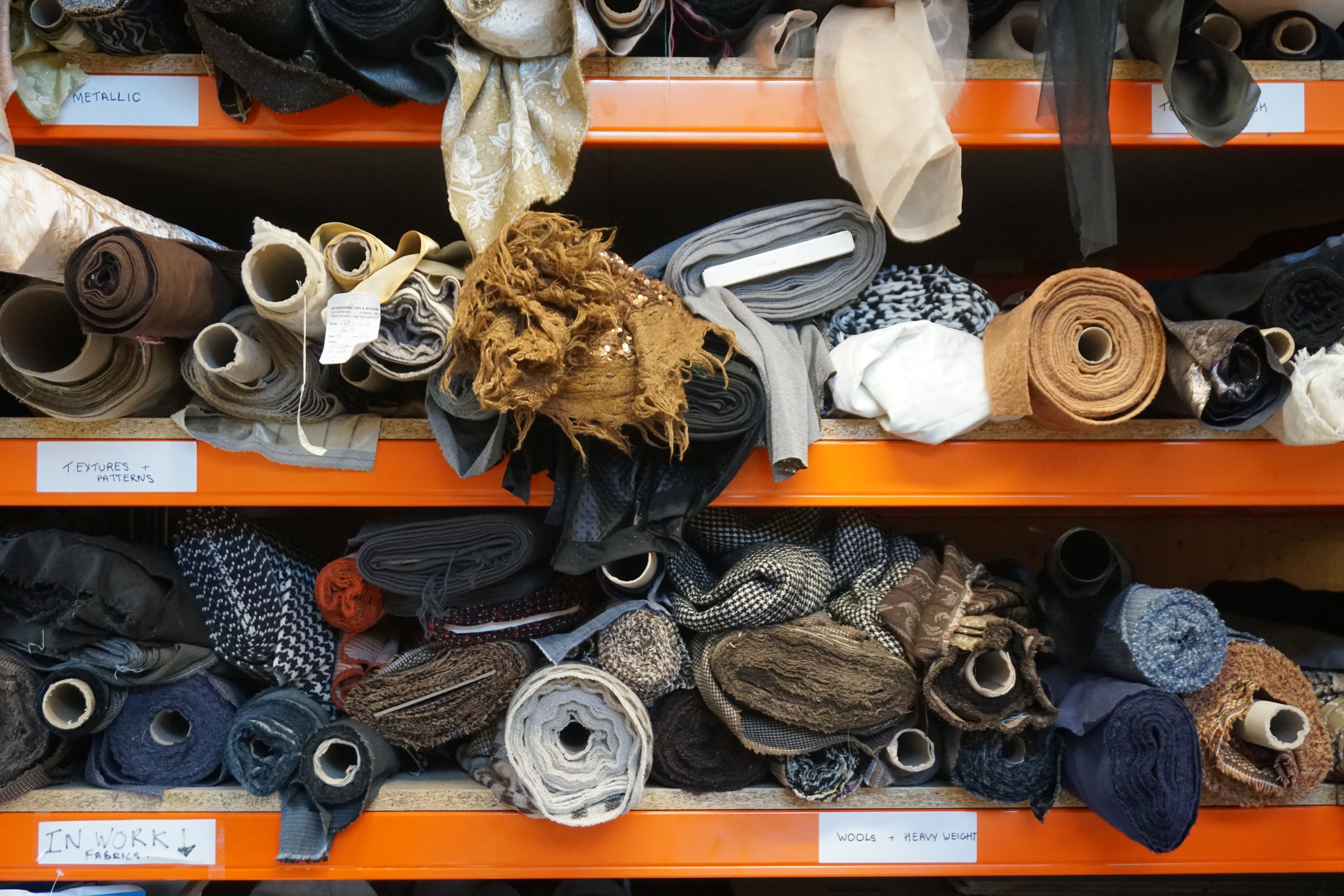 Three orange shelves worth of assorted fabrics.