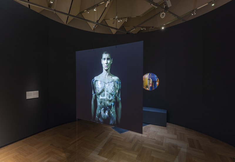 male torso image on black screen in black painted gallery