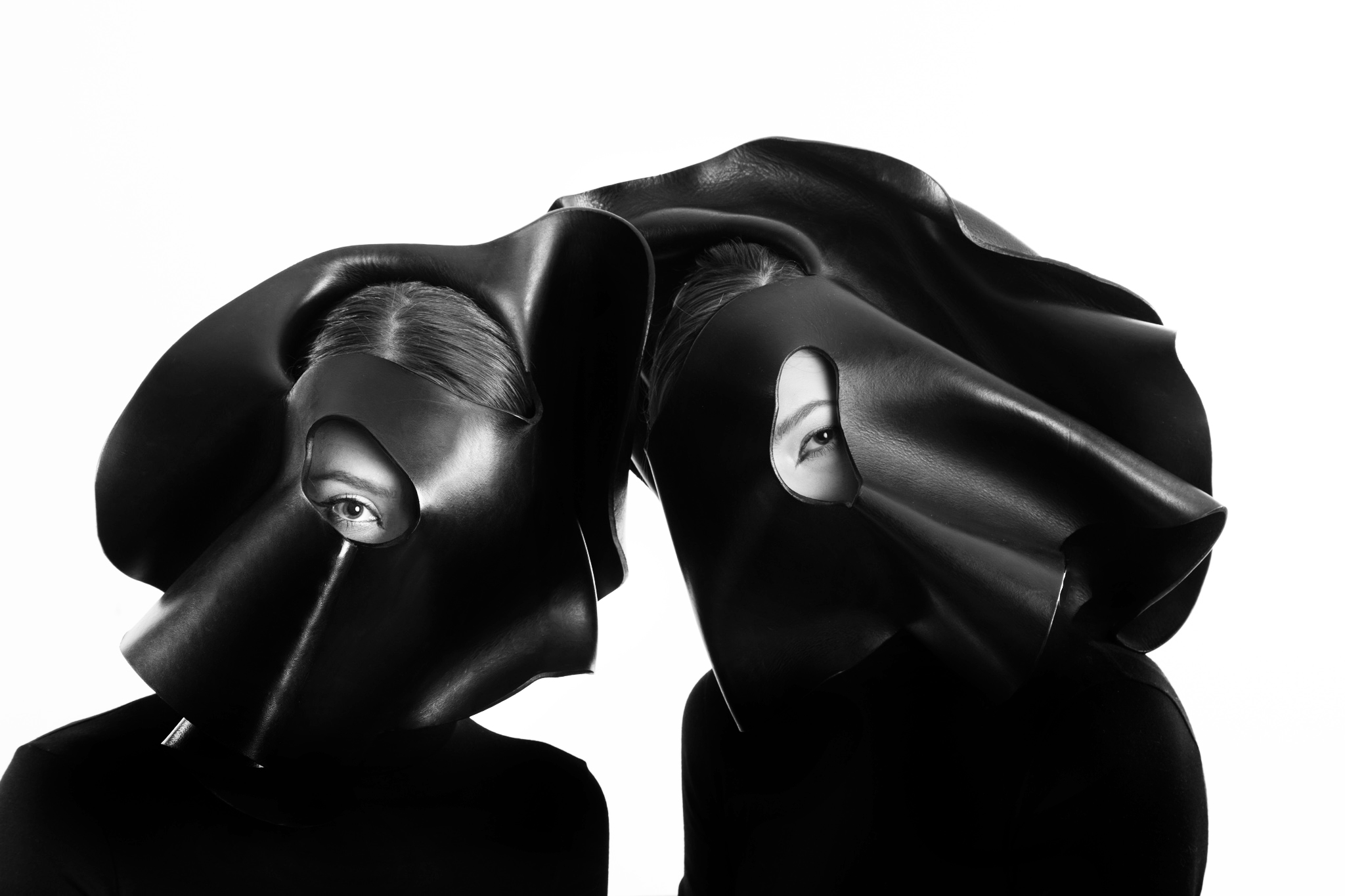 Two models in monochrome image with futuristic black headwear
