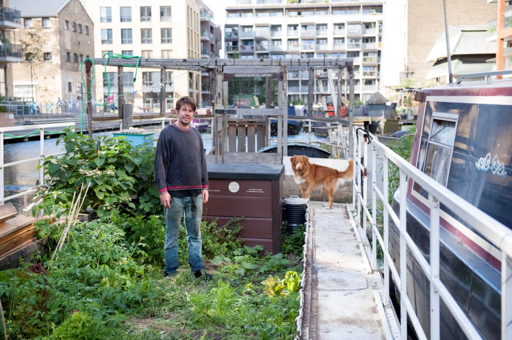 Terry with his dog Manny on their houseboat on the Regents Canal. All 30 residents living on the boats share the gardens. Image by Mary Frances Scott.