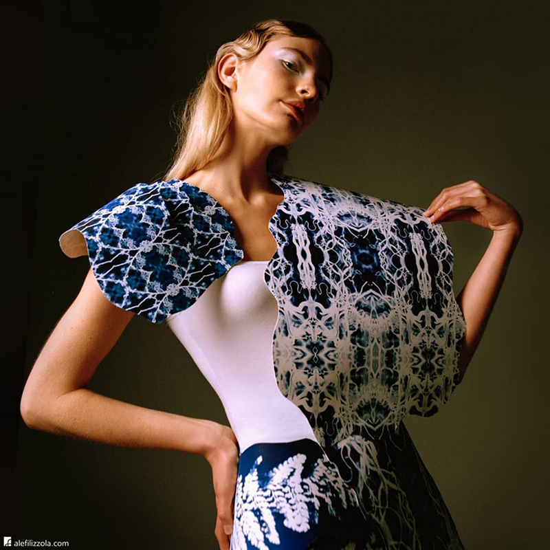 Female model wearing white top and blue and white cape and skirt