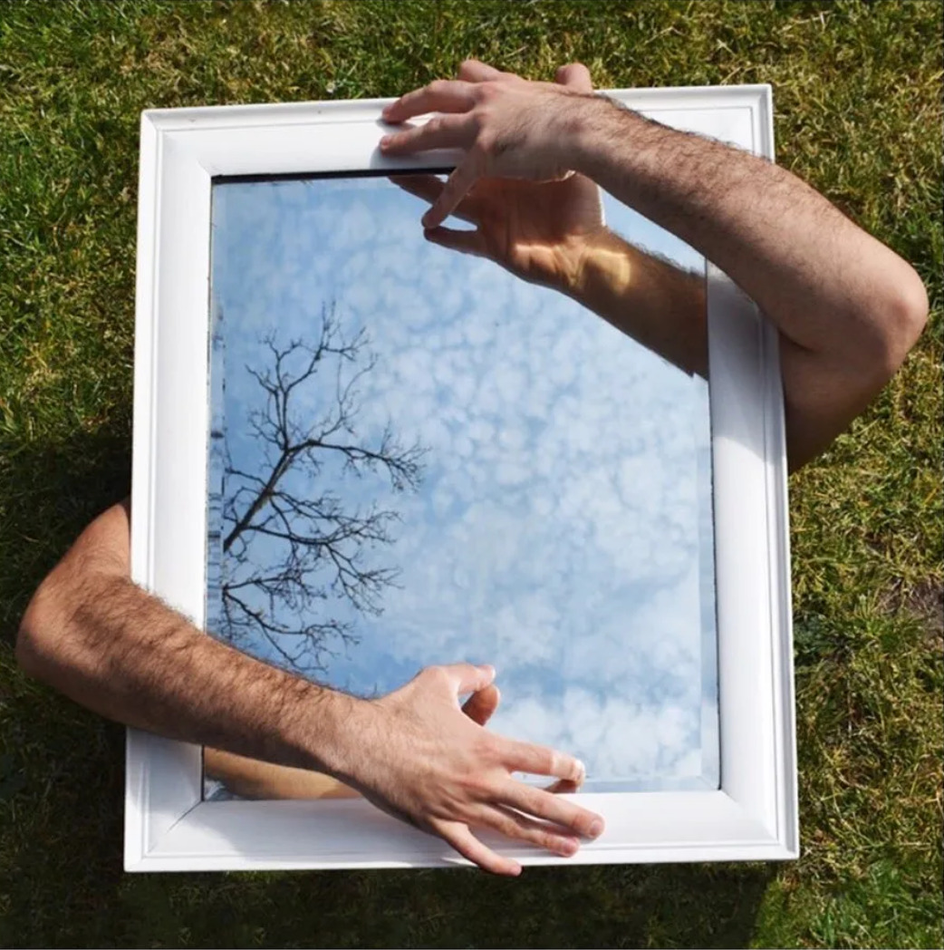 Two arms holding a mirror to the sky 