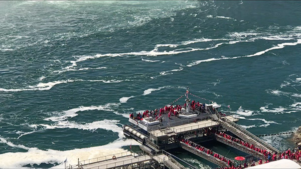 A photograph showing tourists dressed in red getting off a boat