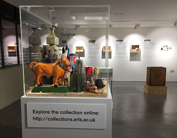 An orange bull stands in a display case with other objects
