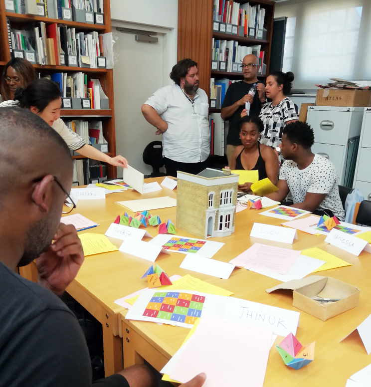 Workshop participants gather around a table covered in bright paper materials