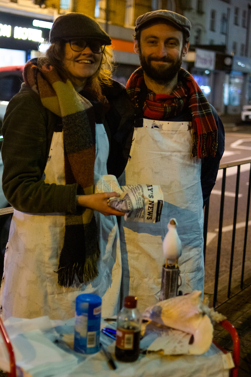 Two figures holding fish and chips