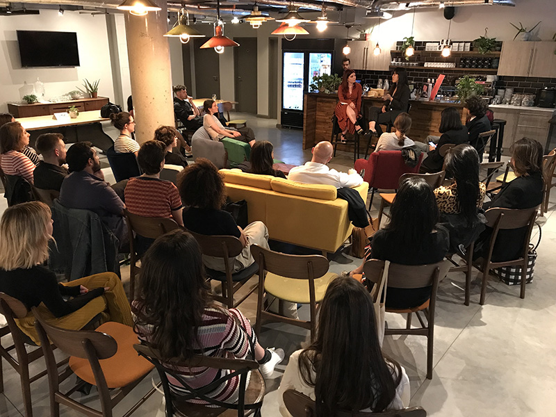 A crowd of people attend a talk in a bar
